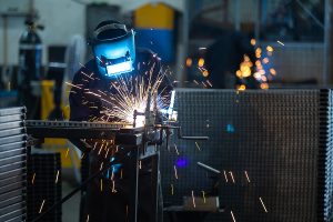Workers Wearing Industrial Uniforms And Welded Iron Mask At Stee
