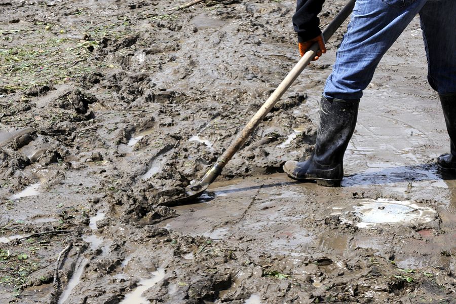 Mudslide Contamination Testing - a person scooping up mud from a slide