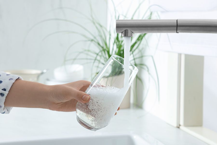 Household water spigot with a person filling a glass with water