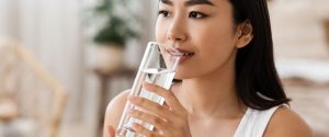 A person drinking water from a clear glass.